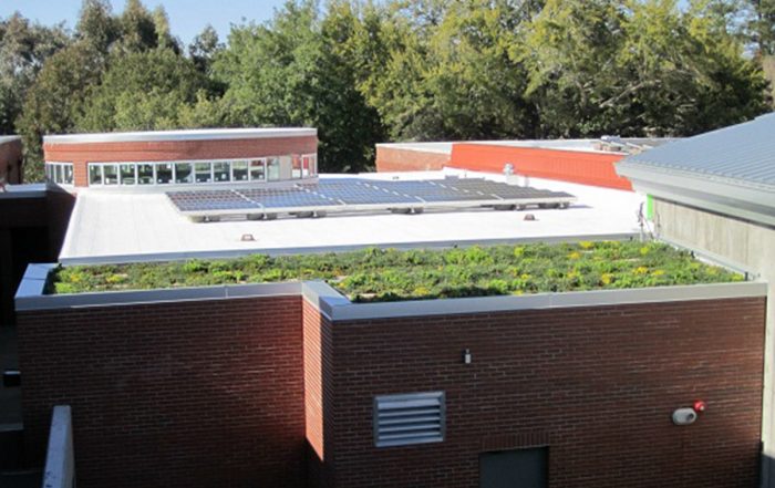 A brick building with a vegetated green roof and solar panels.