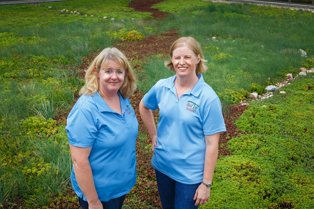 Two women standing on a green living roof.