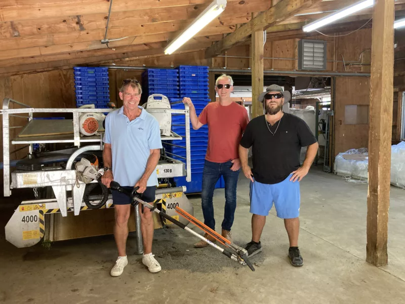 Three men standing in front of some equipment smiling.